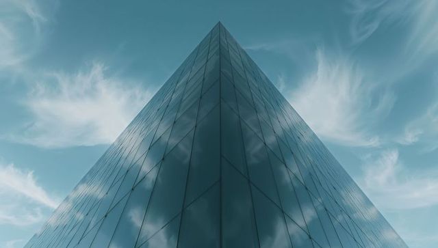 Sleek glass skyscraper reflecting bright cloudscape