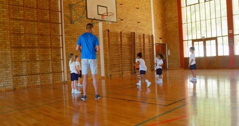Basketball Coach Conducting Training Session with Kids in School Gymnasium