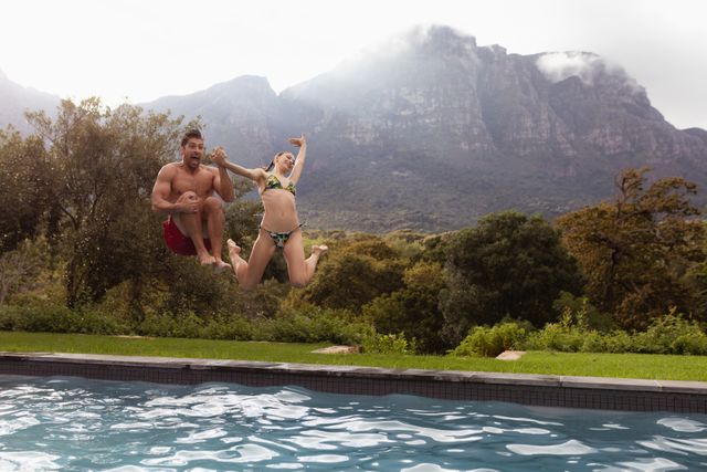Couple jumping together in the swimming pool at backyard - Download Free Stock Photos Pikwizard.com