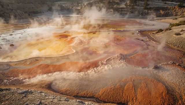 Vibrant geothermal pool steam with mineral terraces