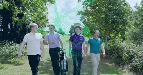 Four men walking on golf fairway wearing colorful polo shirts carrying golf bag on sunny day