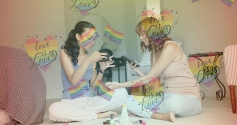 Two women painting nails sharing polish using smartphones, cozy lifestyle rainbow overlay