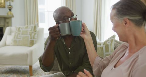 Cheerful Senior Couple Enjoying Coffee in Cozy Living Room