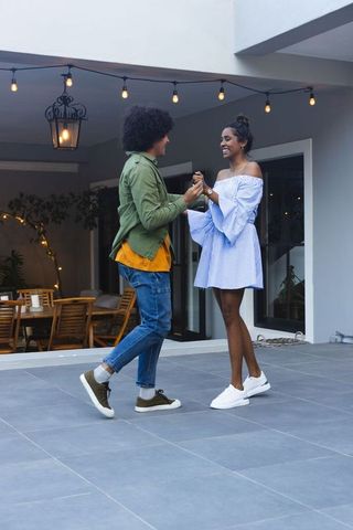 African american couple dancing on covered patio under string lights at dusk