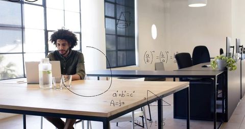 Young professional working on laptop in bright coworking office with math sketches overlay