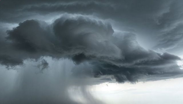 Towering Cumulonimbus Storm Cloud Casting Dark Rain Shafts over Distant Horizon