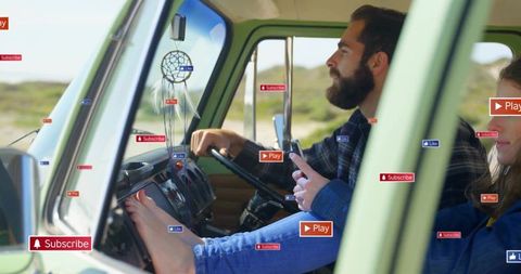Bearded man driving vintage green van while partner relaxing barefoot on dash, coast drive