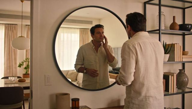 Adjusting wristwatch in round mirror morning routine in minimalist sunlit living room