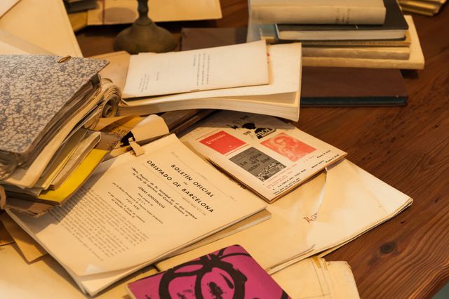 Collection of vintage books and documents scattered on wooden desk. Useful for themes related to history, research, literature, nostalgia, or antique collections. Perfect for use in articles, blogs, or advertising material focused on historical research, literary studies or the charm of old times.