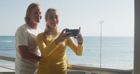 Smiling Couple on Beach Balcony Taking Selfie