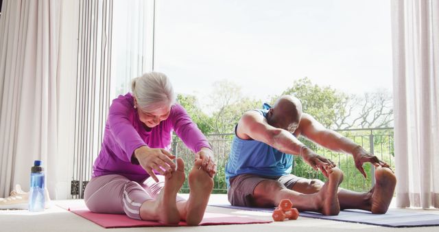 Happy senior diverse couple practicing yoga and stretching. Spending quality time at home and retirement concept.