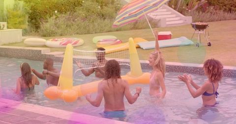 Friends playing inflatable volleyball in backyard pool at colorful summer party