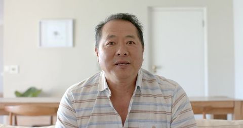 Asian Man Relaxing in Minimalist Living Room with Scandinavian Decor