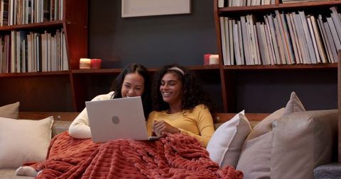 Happy Diverse Women Relaxing Together with Laptop and Blanket