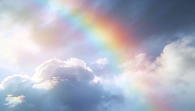 Glowing Diagonal Rainbow Arching Over Sunlit Cumulus Cloudscape