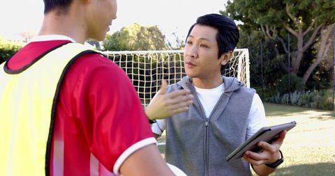 Soccer coach guiding teenage player on training field
