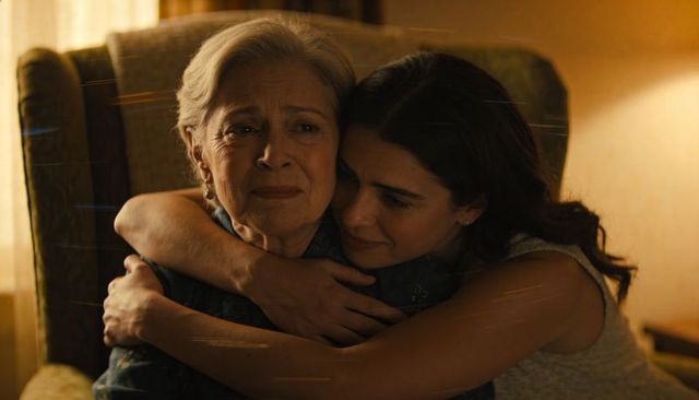 Granddaughter hugging grandmother in tender living room embrace conveying love and comfort