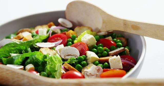 This vibrant salad features a blend of fresh vegetables including cherry tomatoes, lettuce, green peas, mushrooms, and tofu, presented in a white bowl. Suitable for use in healthy living articles, vegan food blogs, nutritional guides, and recipe websites promoting a healthy lifestyle.