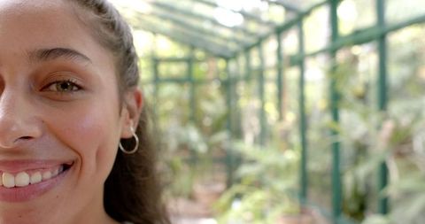 Smiling woman relaxing in greenhouse with hoop earring