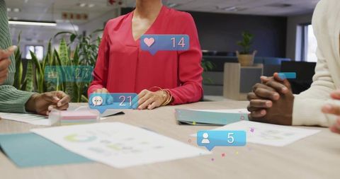 Female leader presenting analytics with social media notifications during collaborative office meeti