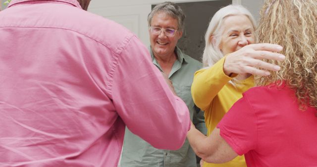 Image of happy caucasian senior couple welcoming friends. retirement lifestyle, spending quality time with friends.