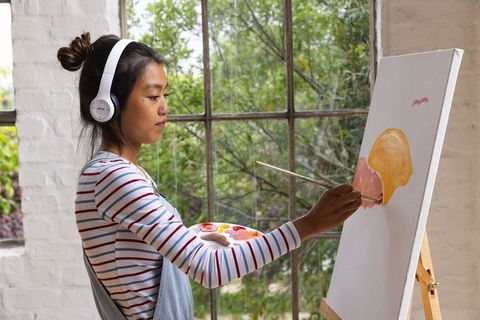 Creative young woman painting at easel in art studio