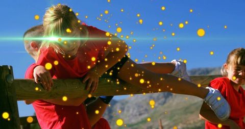 Caregiver supporting child balancing on beam with golden light in mountain playground