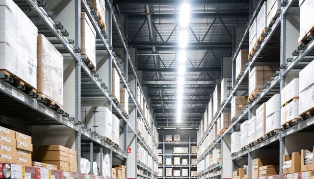 Warehouse aisle featuring tall pallet racking, stacked cartons and linear led lighting