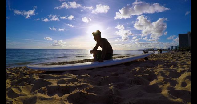 Young Pacific Islander man prepares to surf at the beach, with copy space. He's crouched on his board, capturing the essence of outdoor adventure.