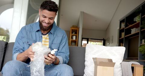 Man Unwrapping Product on Sofa in Bright Living Room