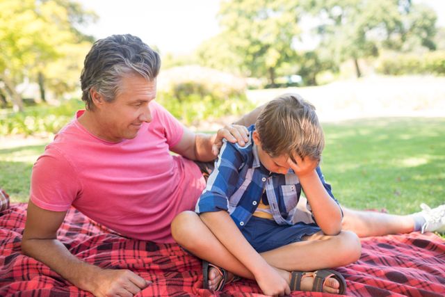 Father Consoling Son at Picnic in Park on Sunny Day - Download Free Stock Photos Pikwizard.com
