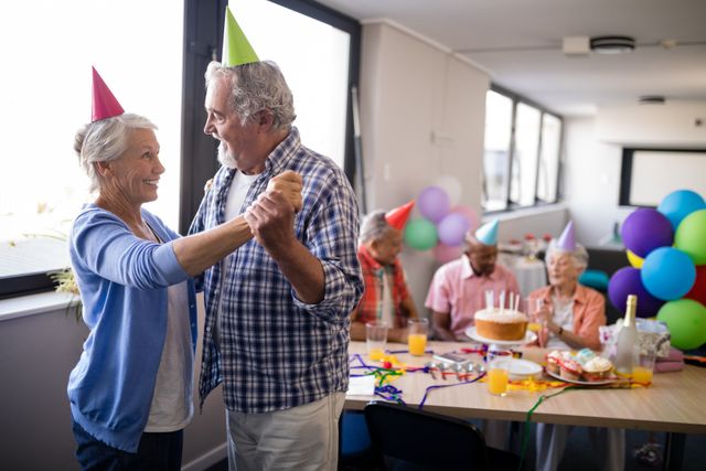 Smiling senior couple dancing by friends enjoying at birthday party