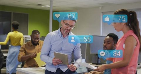 Team reviewing tablet with social notifications in modern open-plan office collaboration