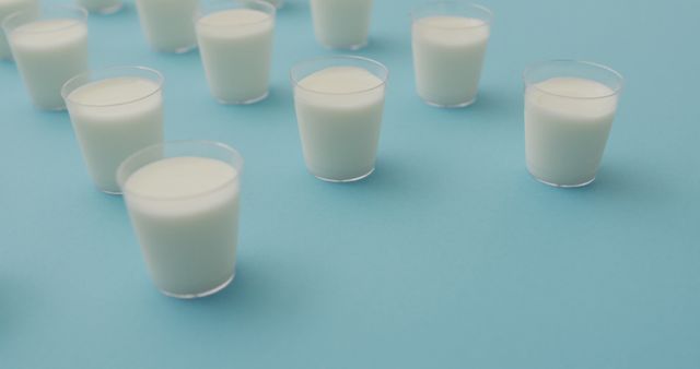Image of row of glasses of milk on blue background. dairy products and healthy organic nutrition.