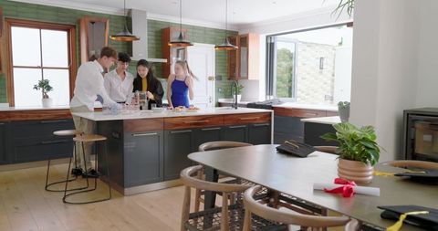 Diverse friends chatting and serving appetizers around modern wooden kitchen island