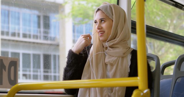 Smiling Young Woman in Hijab Listening to Music on Bus - Download Free Stock Images Pikwizard.com