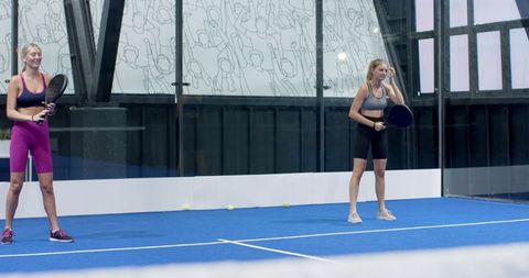 Athletic Women Playing Padel in Modern Indoor Stadium