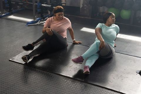 African american women stretching in gym performing seated spinal-twist for mobility and flexibility