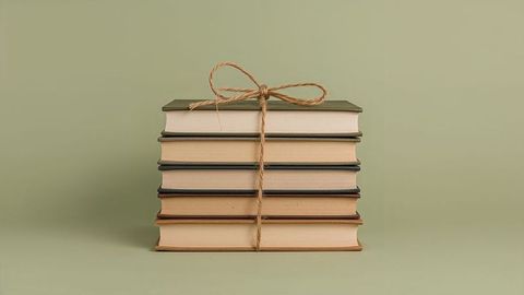 Stack of hardcover books tied with twine bow in minimalist setting