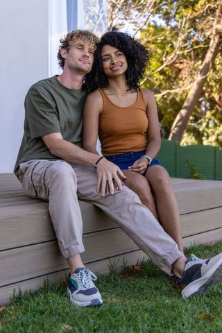Couple relaxing on backyard deck holding hands sharing casual sunny weekend moment