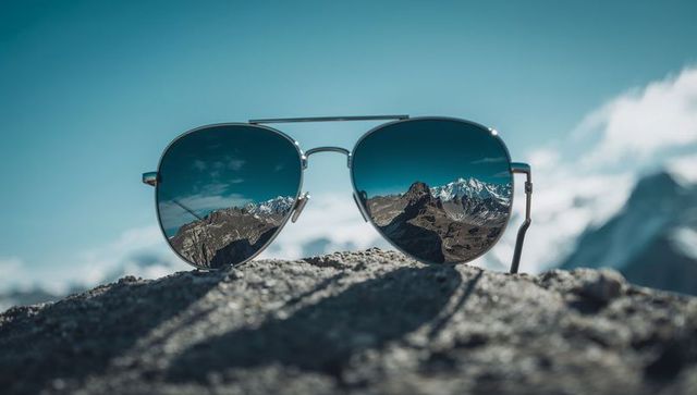 Aviator Sunglasses Reflecting Snow-Capped Mountain Peaks Close-Up