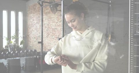 Woman adjusting smartwatch in industrial gym loft while preparing workout