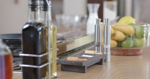 Dark stone salt tray with wooden scoops and stainless grinders on modern wood countertop