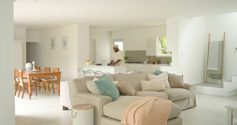Man working on laptop at kitchen island in airy neutral open-plan living room