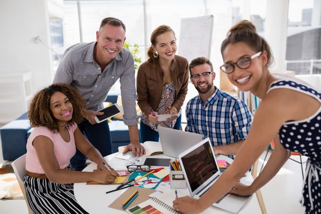 Group of diverse professionals collaborating on a project in a modern office. Ideal for illustrating teamwork, business meetings, and creative work environments. Suitable for use in business presentations, corporate websites, and marketing materials.
