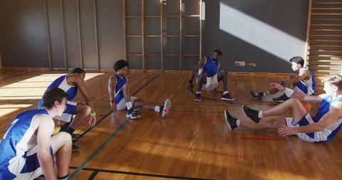 High school basketball team stretching on wooden gym floor with climbing bars