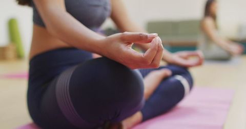 Woman Practicing Yoga in Lotus Position on Yoga Mat in Studio