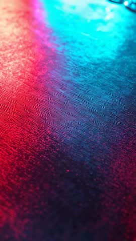 Vertical video: Neon reflections on textured surface in red and blue for moody abstract background