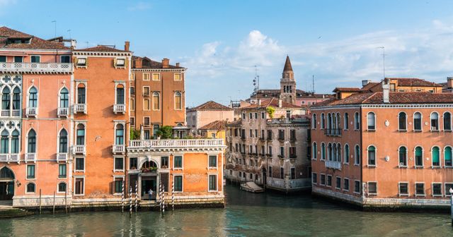 Beautiful view of a Venice canal lined with charming historic buildings under a clear blue sky. Ideal for use in travel blogs, tourism advertisements, educational materials about European cities, and posters highlighting cultural destinations.