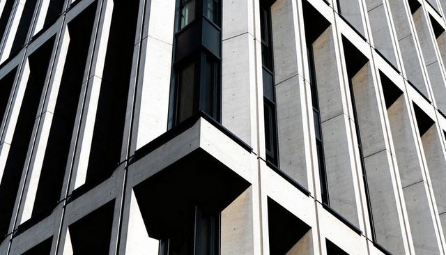 Angular concrete facade with deep shadows and cantilevered window bays, modern architecture